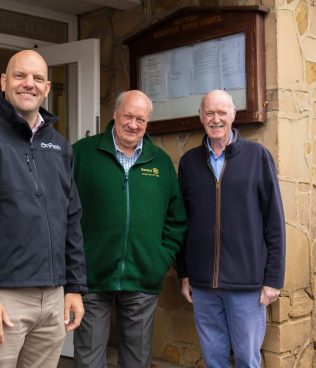 3 men stood outside a community centre in bishopton, which has recieved wind farm community funding for major repairs