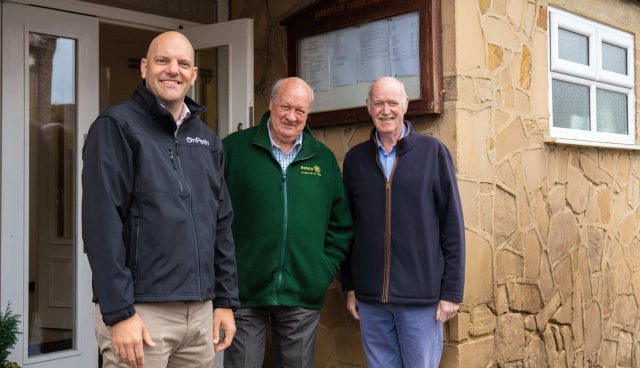 3 men stood outside a community centre in bishopton, which has recieved wind farm community funding for major repairs