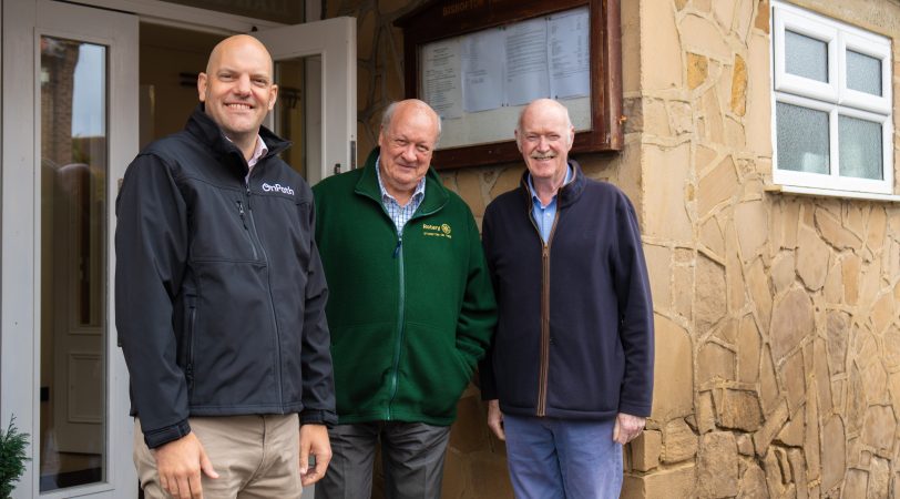 3 men stood outside a community centre in bishopton, which has recieved wind farm community funding for major repairs