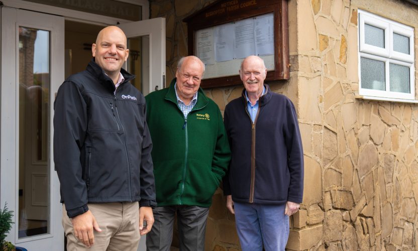 3 men stood outside a community centre in bishopton, which has recieved wind farm community funding for major repairs